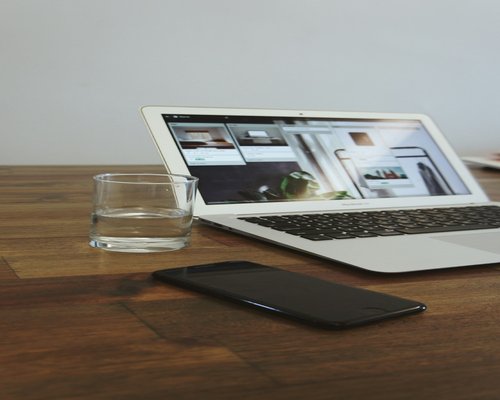 A laptop on a wooden table alongside a glass of water, emphasizing hydration and structured breaks